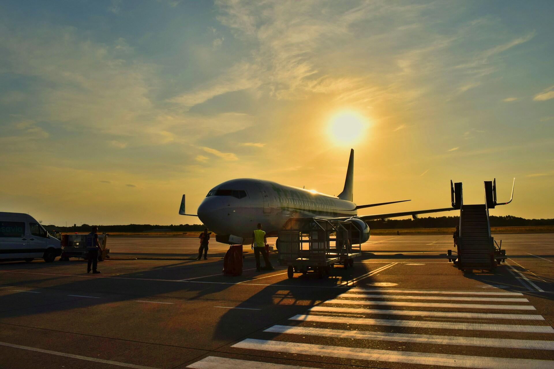 Fly parkert på flyplass med solnedgang i bakgrunnen.