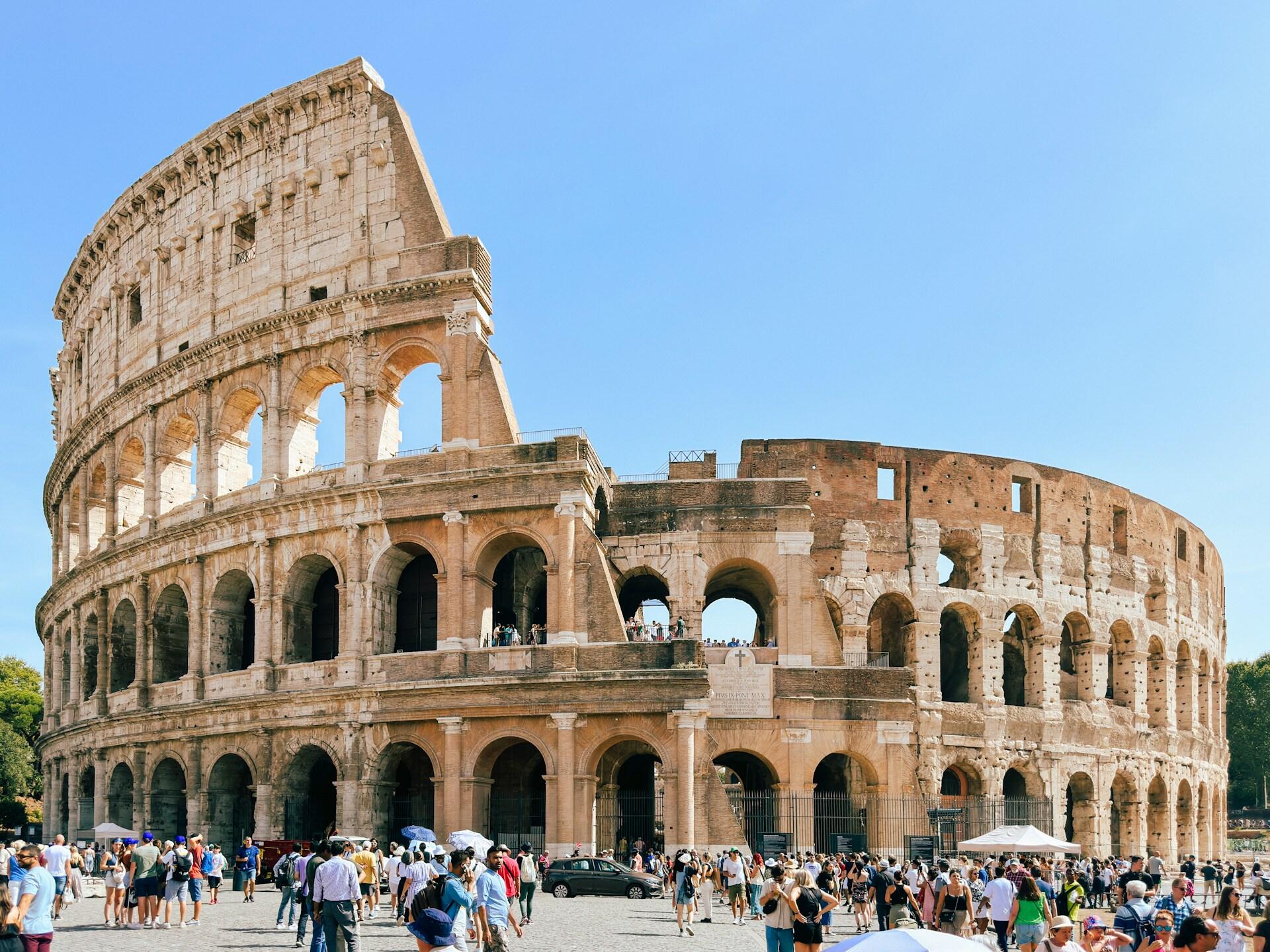 Colosseum i Roma på en varm sommerdag med massevis av turister utenfor.