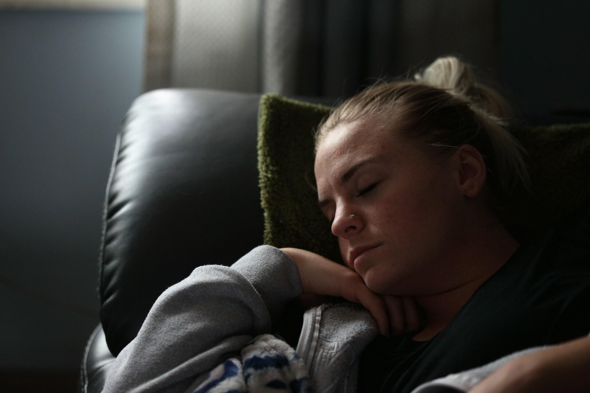 Kvinne hviler på sofa med hodet på en grønn pute