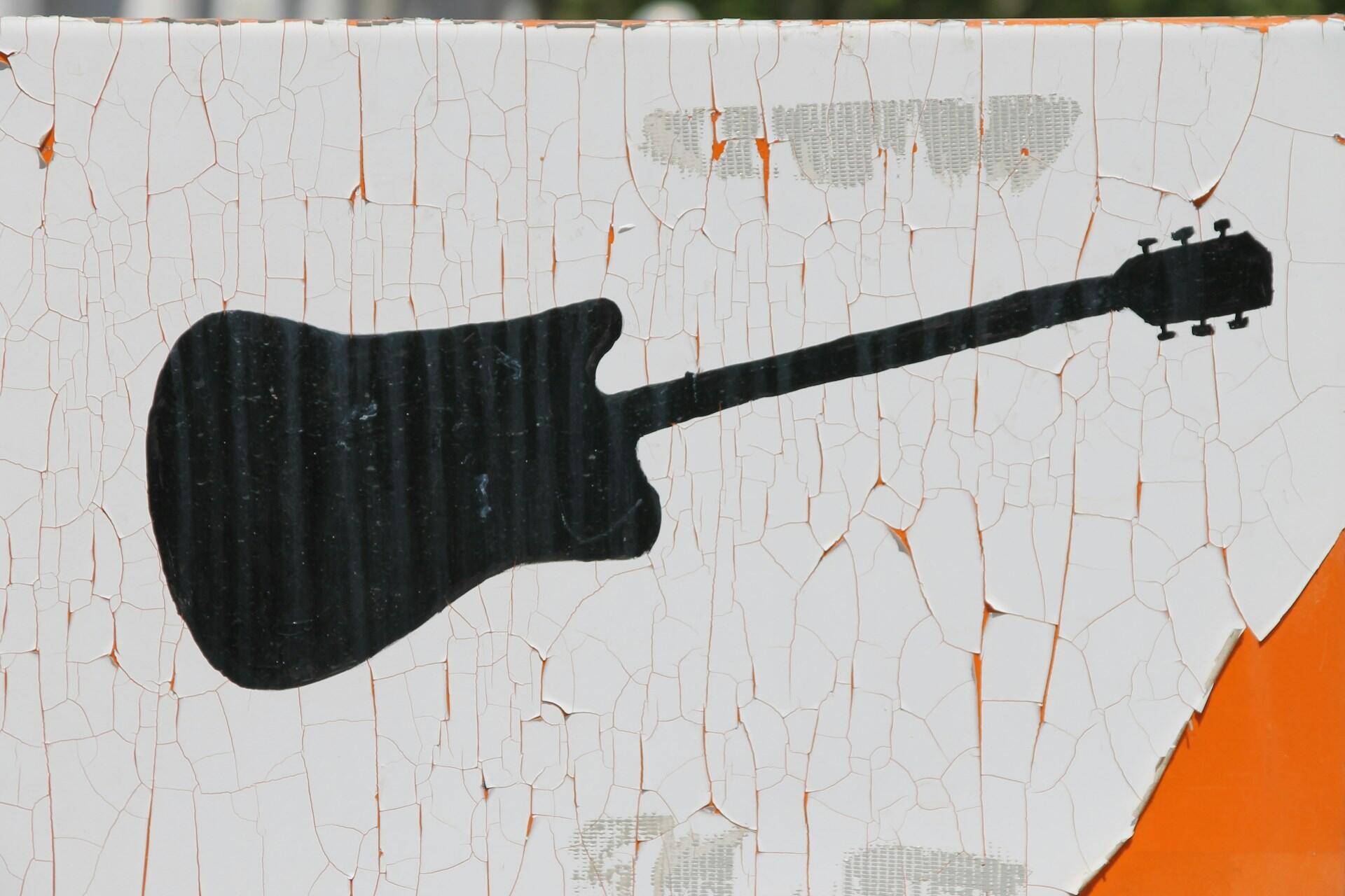Silhuett av en elgitar malt på sprukket overflate
