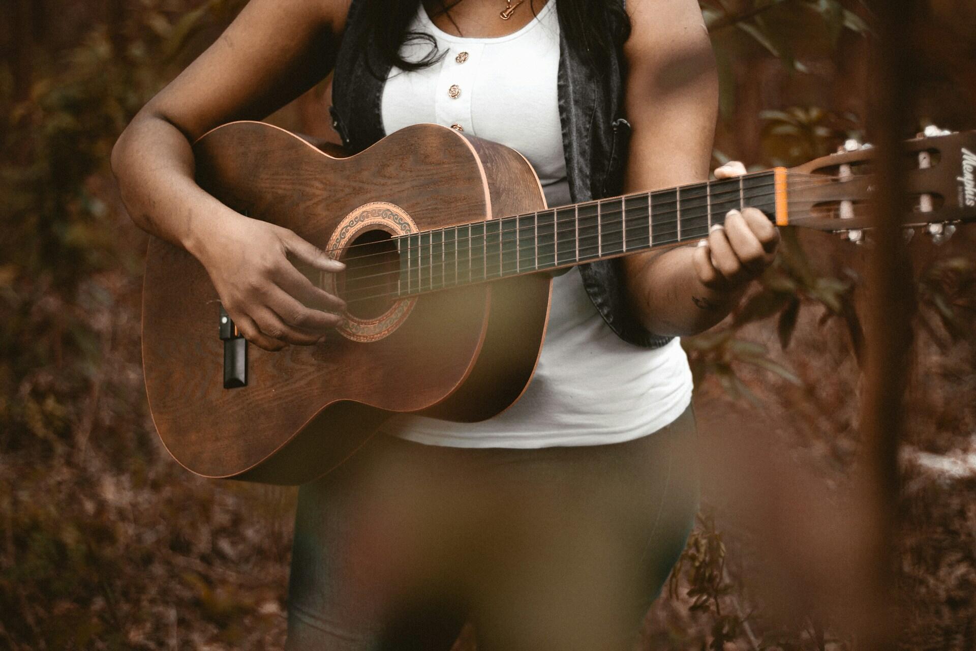 Person som spiller akustisk gitar ute i naturen