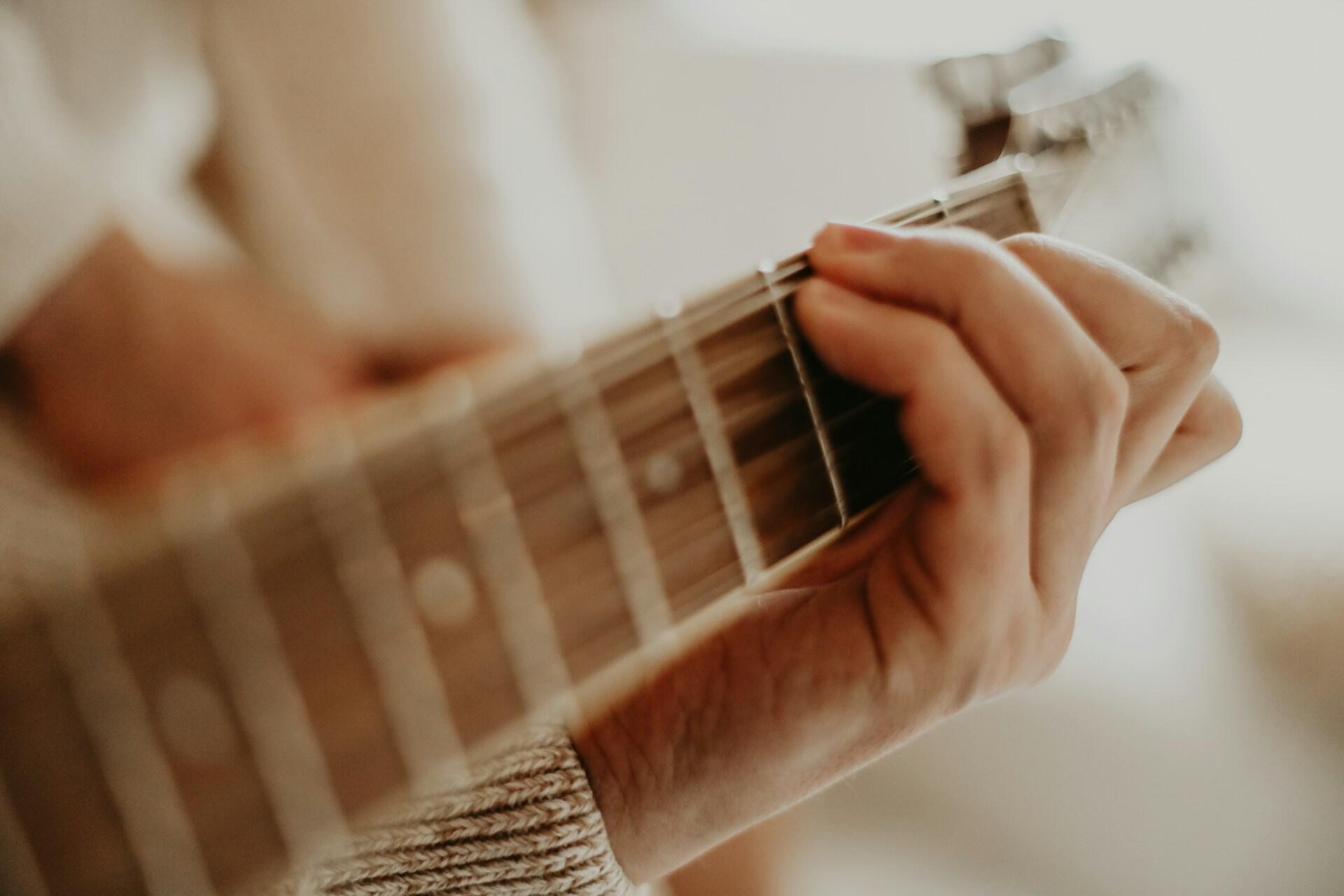 Nærbilde av en hånd som holder grep på gitarhalsen.