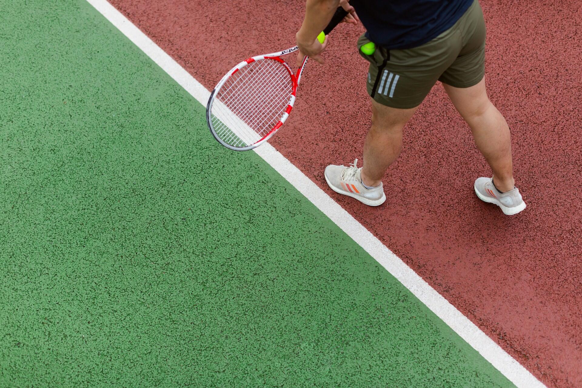 Tennisspiller forbereder en serve på rød og grønn tennisbane