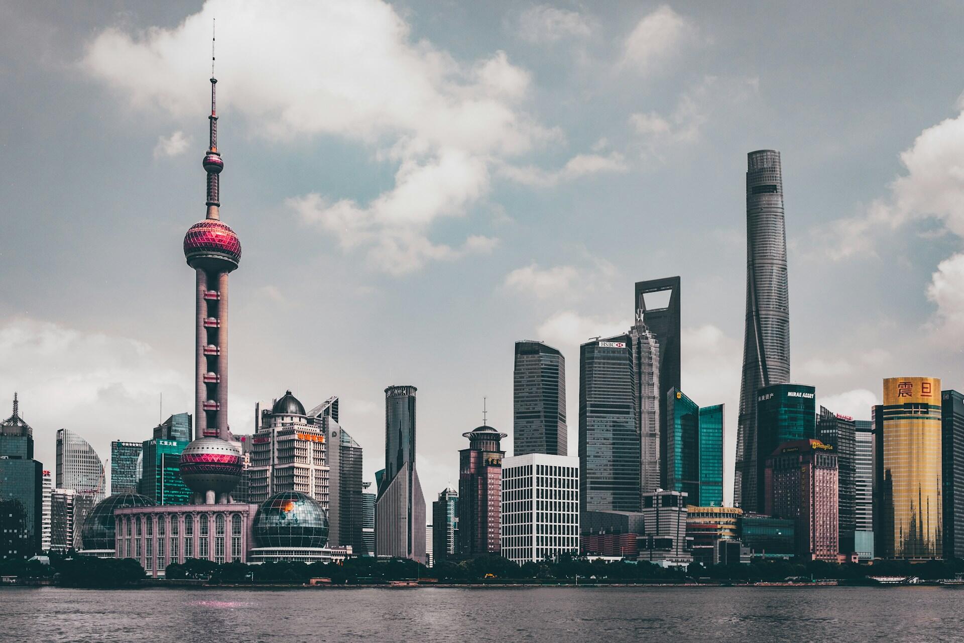 Den moderne kinesiske byen Shanghai med ulike former på bygninger ved vannet.