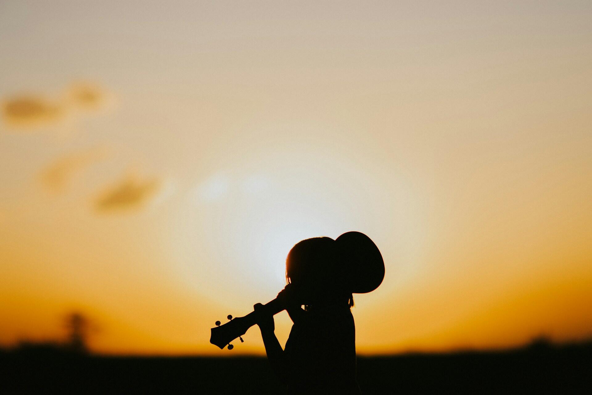 Silhuett av person med gitar i solnedgang