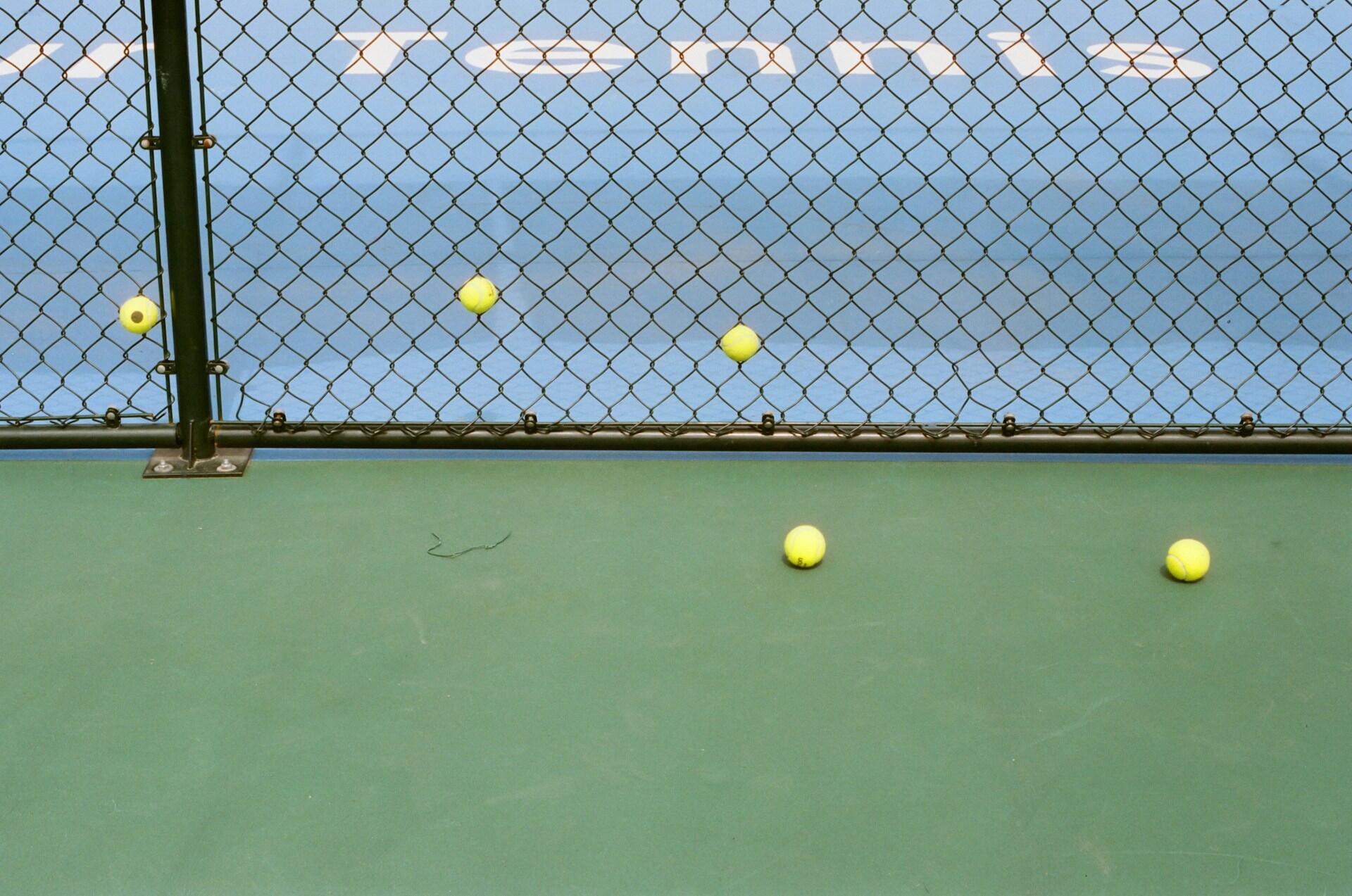 Tennisballer ved et gjerde på en blå bane