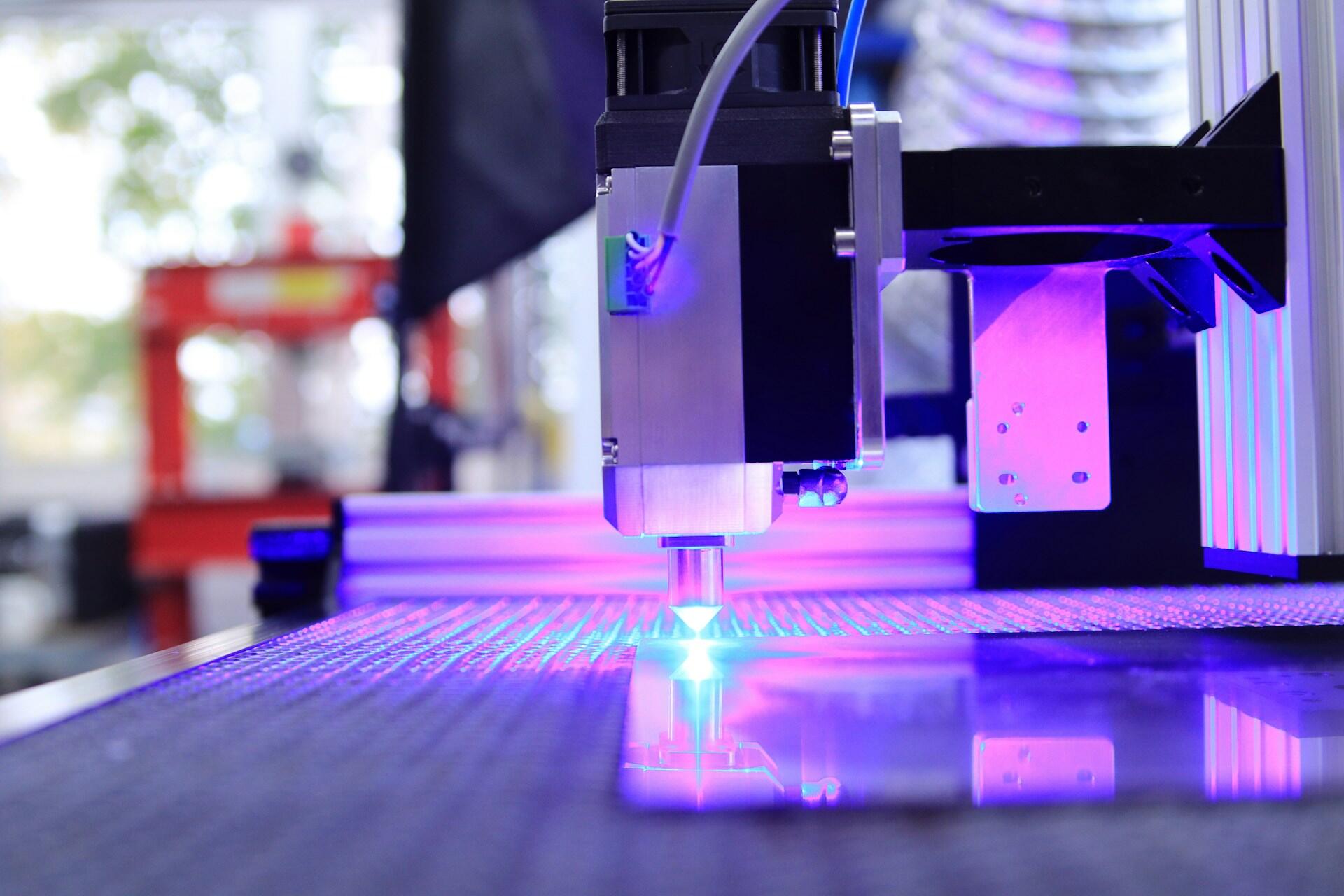 Avansert 3D-printer med lilla og blå belysning som printer objekt på byggeplattform