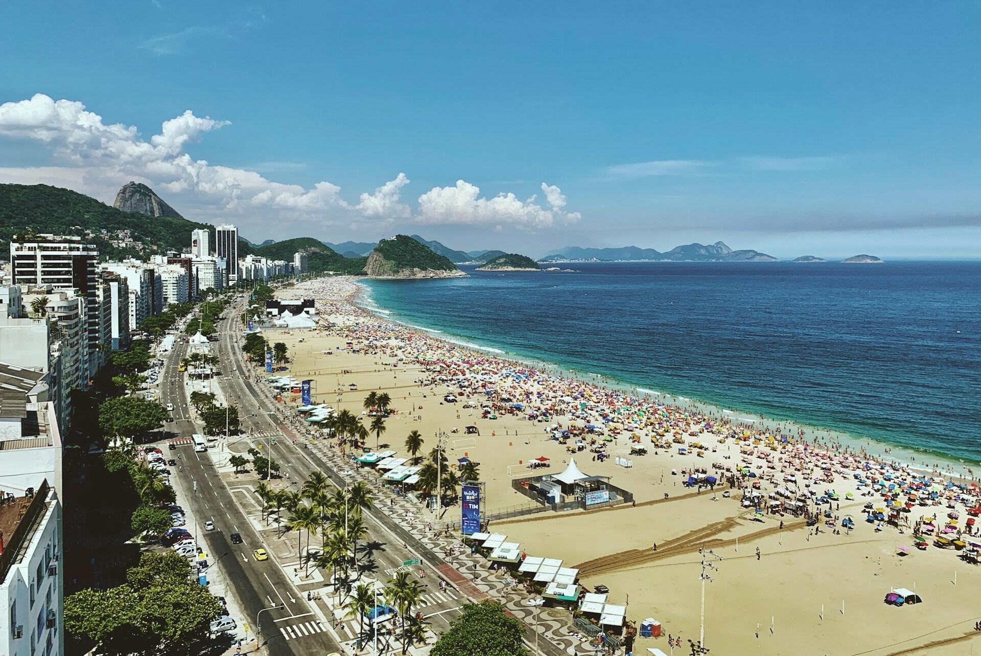 Luftfoto av Copacabana strand i Rio de Janeiro med hvit sand, blått hav og høye bygninger langs kysten