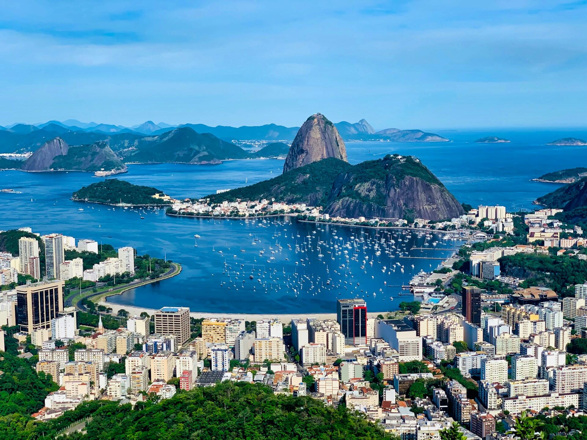 Panoramautsikt over Rio de Janeiro by med Sukkertoppfjellet, blå hav og hundrevis av båter i havnen