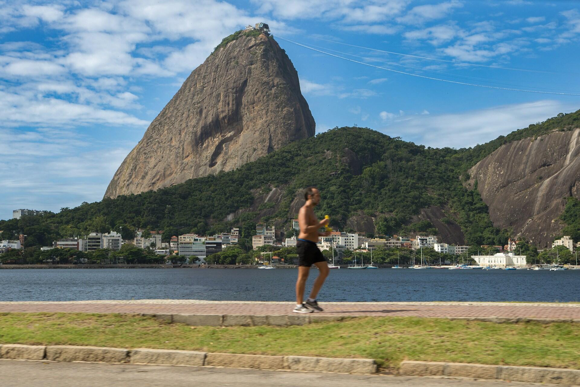 Jogging ved Sukkertoppen i Rio de Janeiro med blå himmel og båter i bakgrunnen