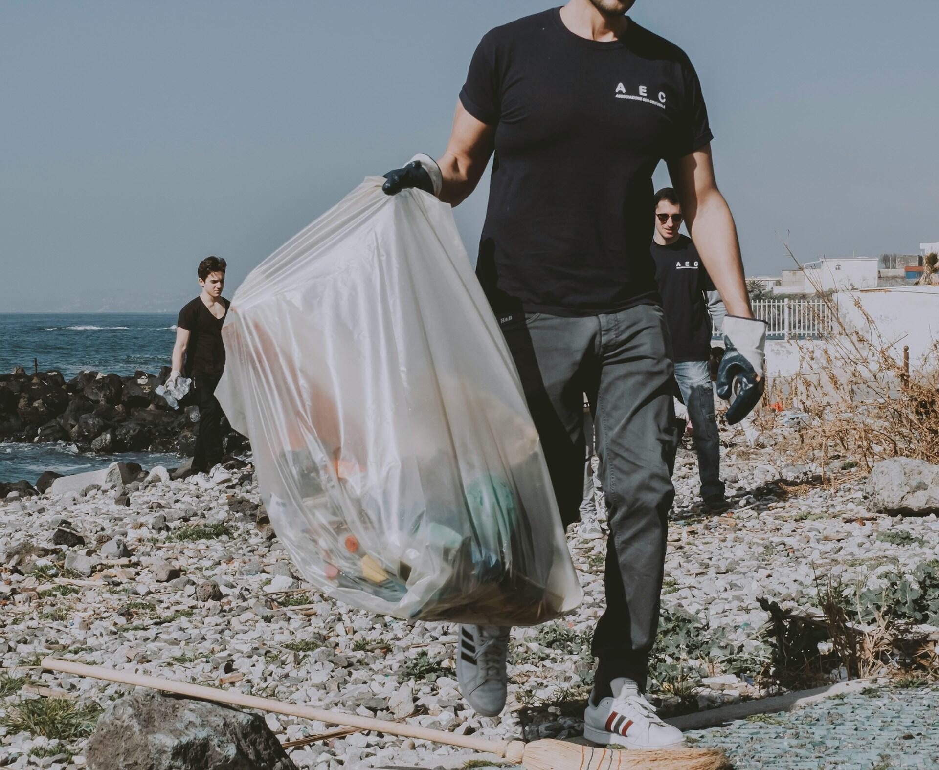 Mann plukker søppel på en strand
