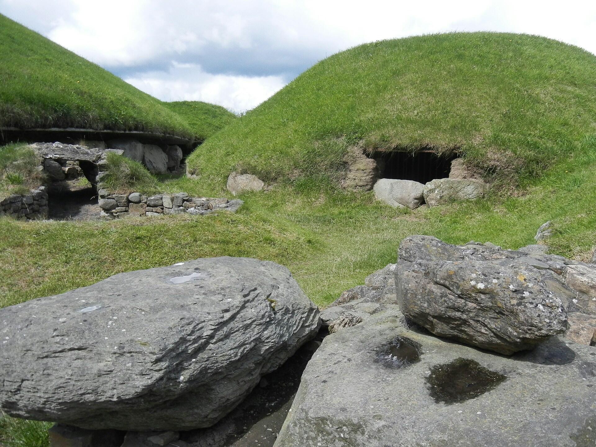 Steingrav og grønne jordhauger ved Knowth i Irland.