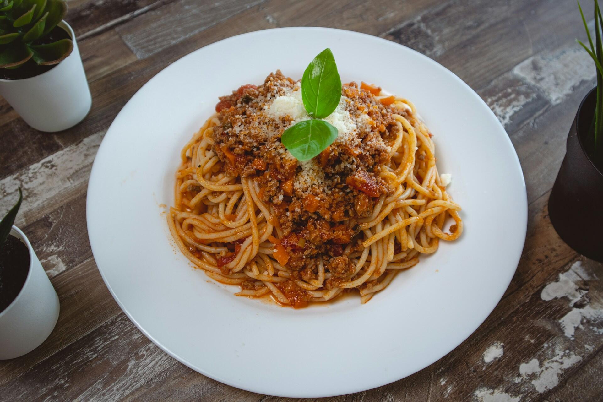 Hvit tallerken med spaghetti og kjøttsaus.