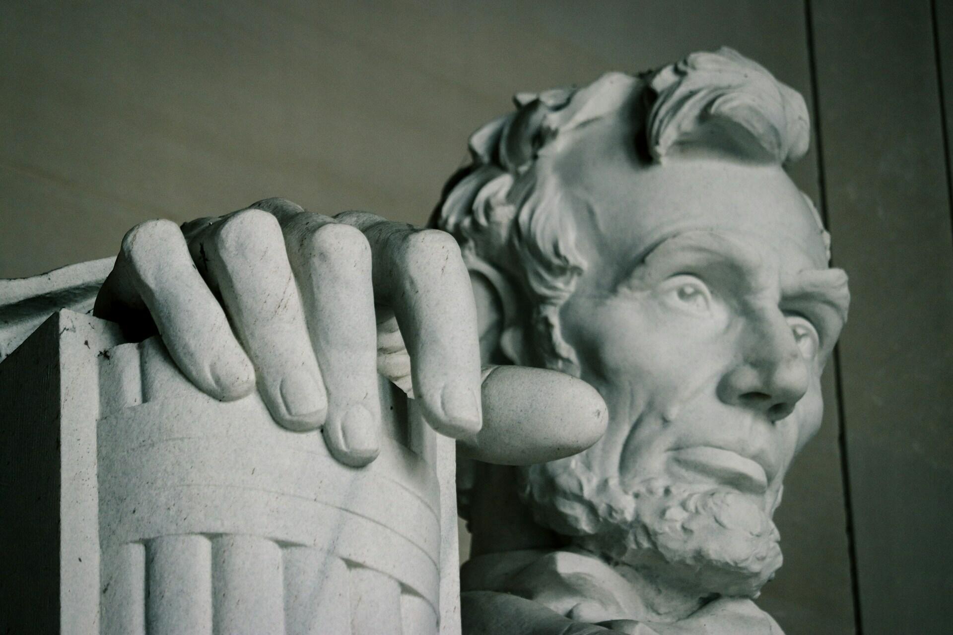 Nærbilde av Abraham Lincoln-statuen i Lincoln Memorial, som viser presidentens rolige ansikt og hånd hvilende på en søyle.