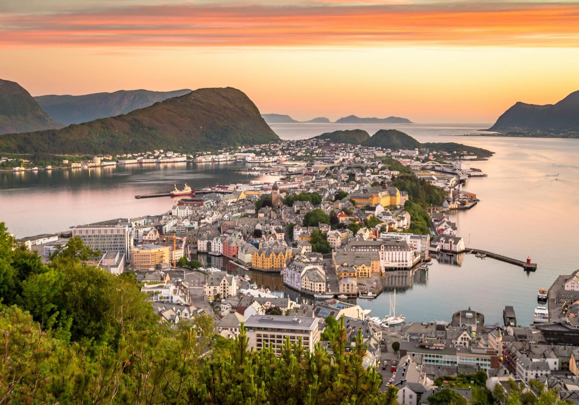 Bilde av Ålesund by tatt fra en ås, med solnedgangen over havet bak