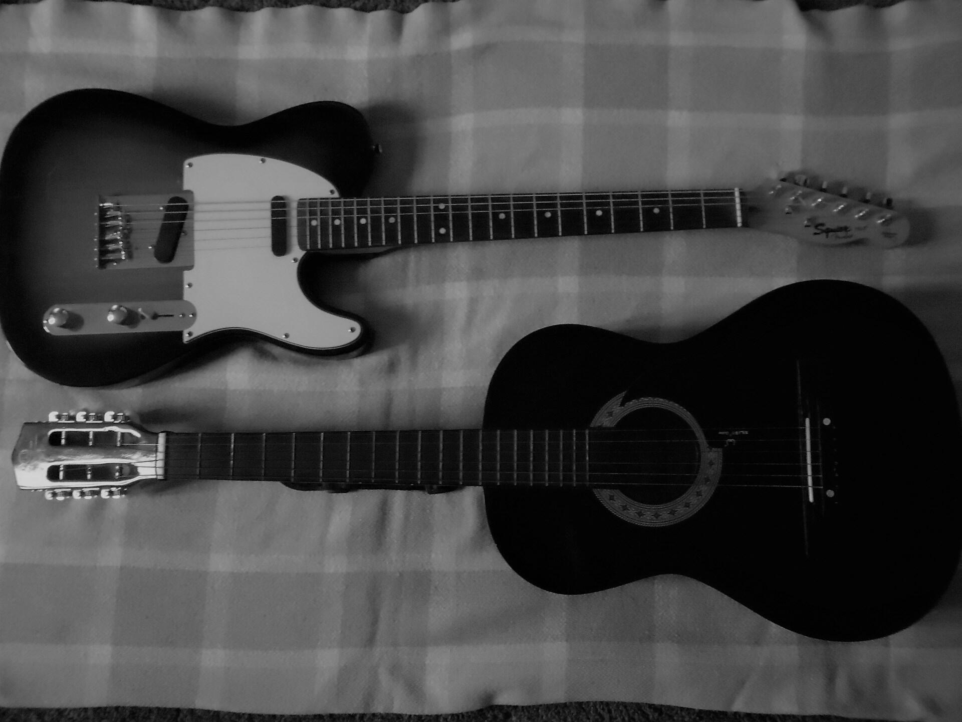 Akustisk og elektrisk gitar side om side, svart-hvitt-bilde.