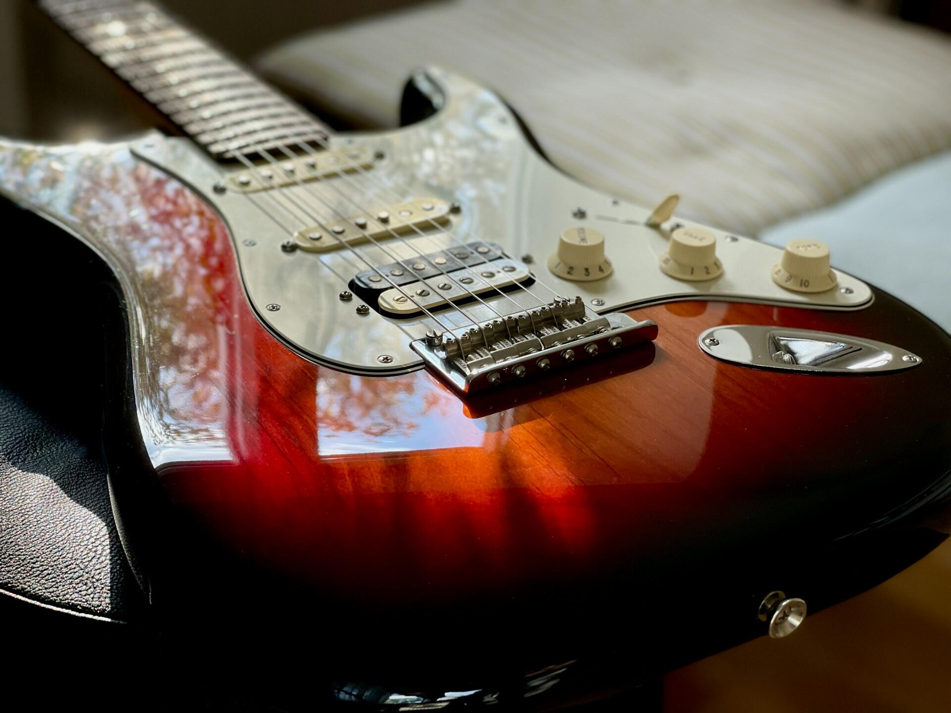 Rød Fender Stratocaster elgitar i sollys, et klassisk bluesinstrument.