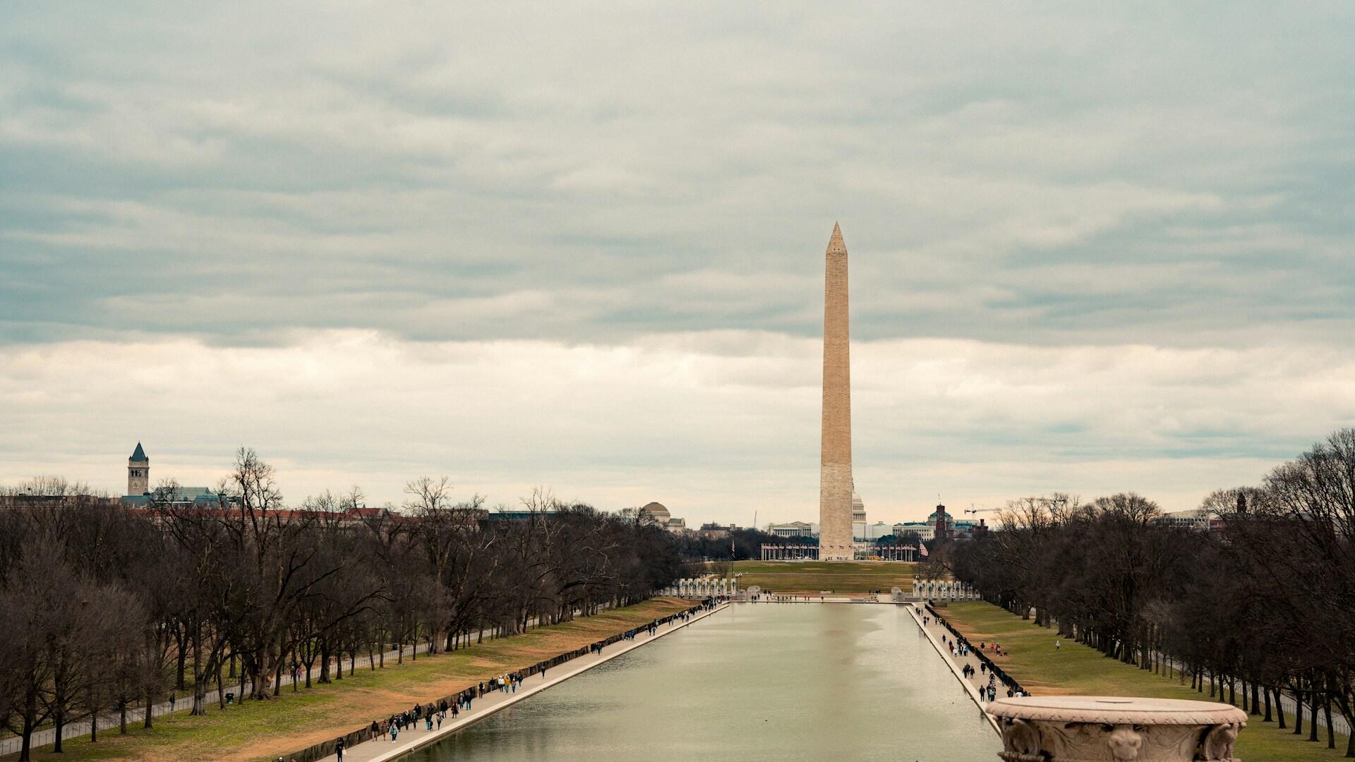 Washington Monument sett fra Lincoln Memorial, med refleksjonsdammen og besøkende langs veien.