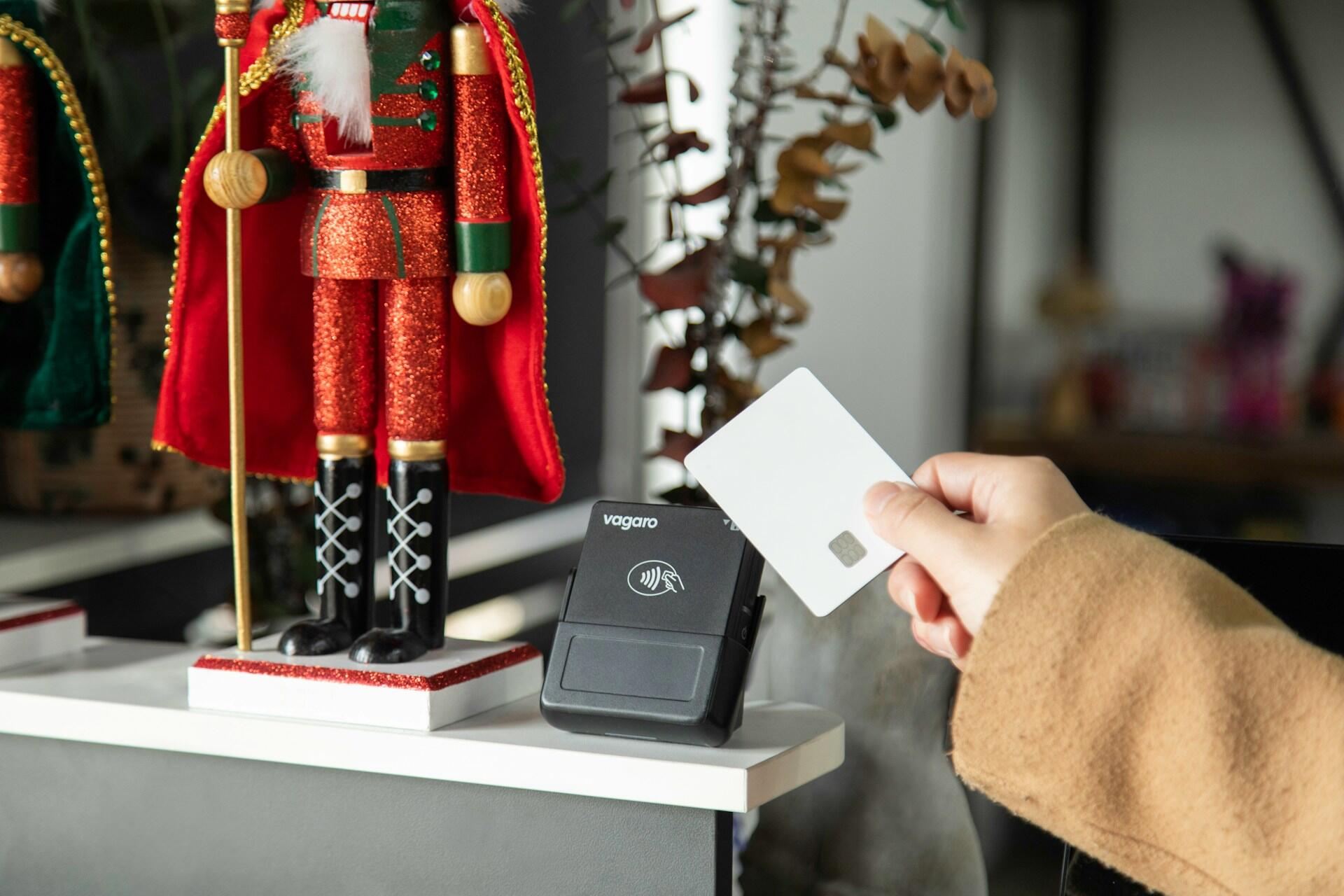 Hånd betaler trådløst med en hvitt bankkort