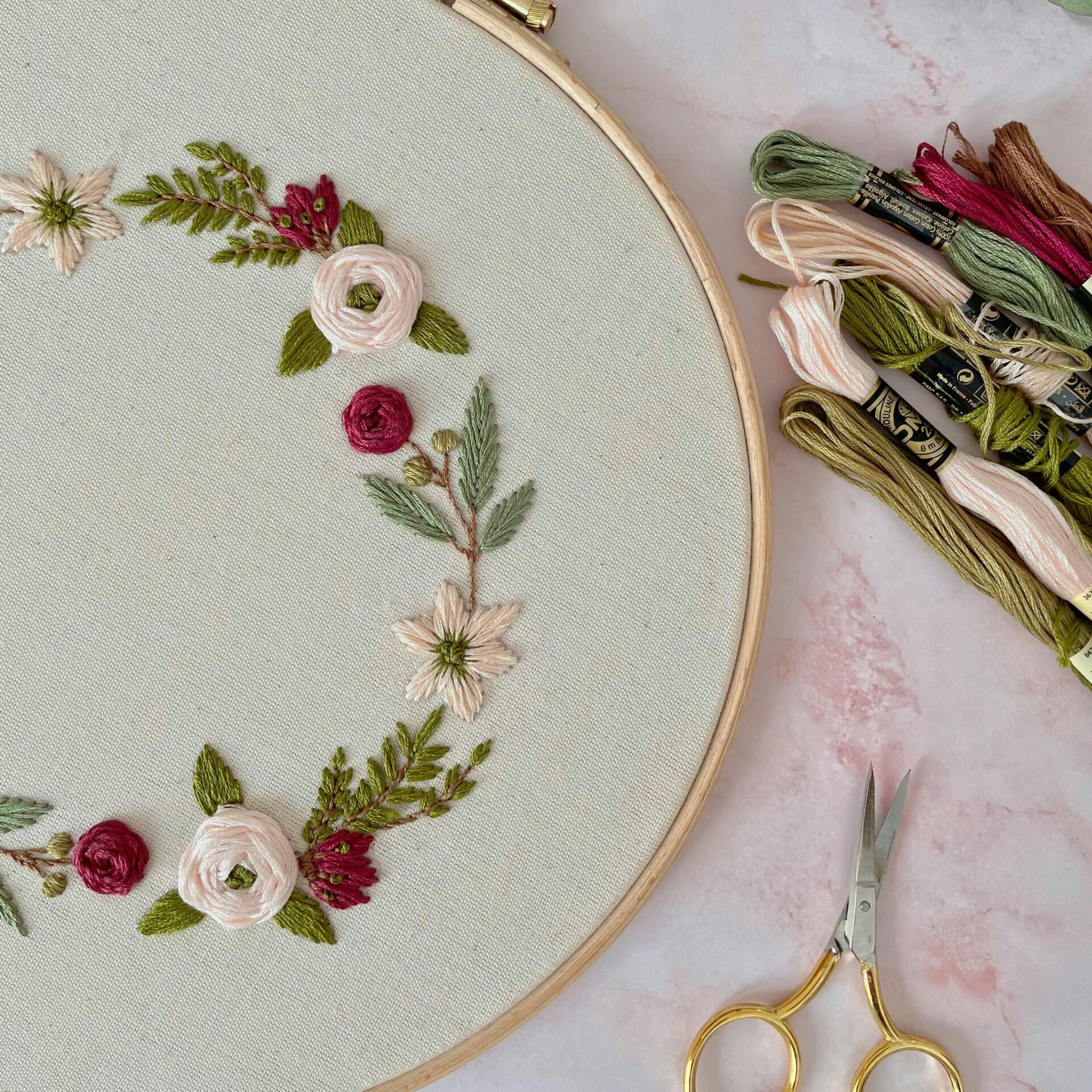 Broderte blomster med broderingstråd ved siden av