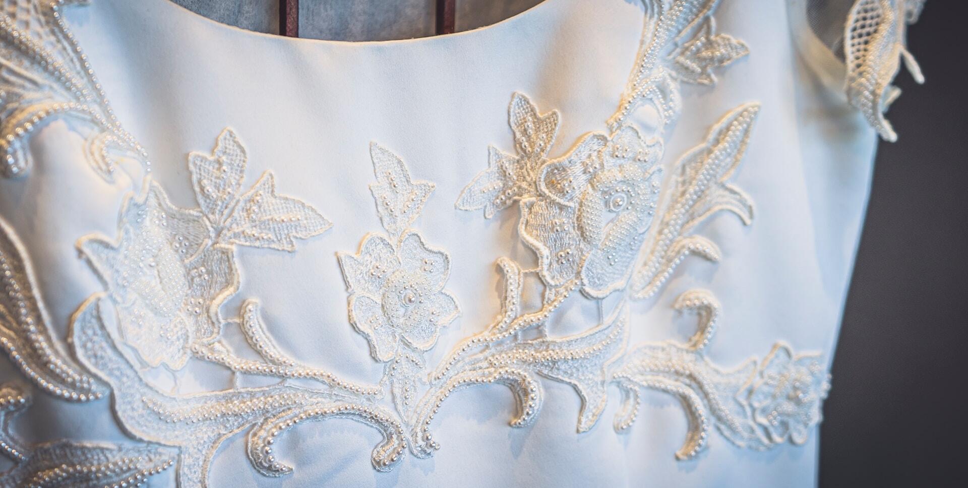 Hvitt blondebroderi på kjole med perler