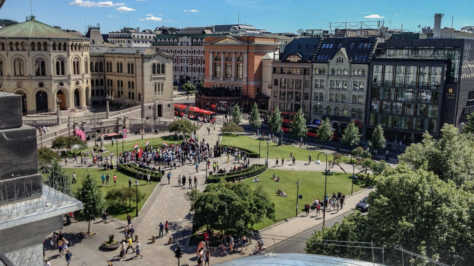 Stortinget i Oslo med folkemengde utenfor på en sommerdag