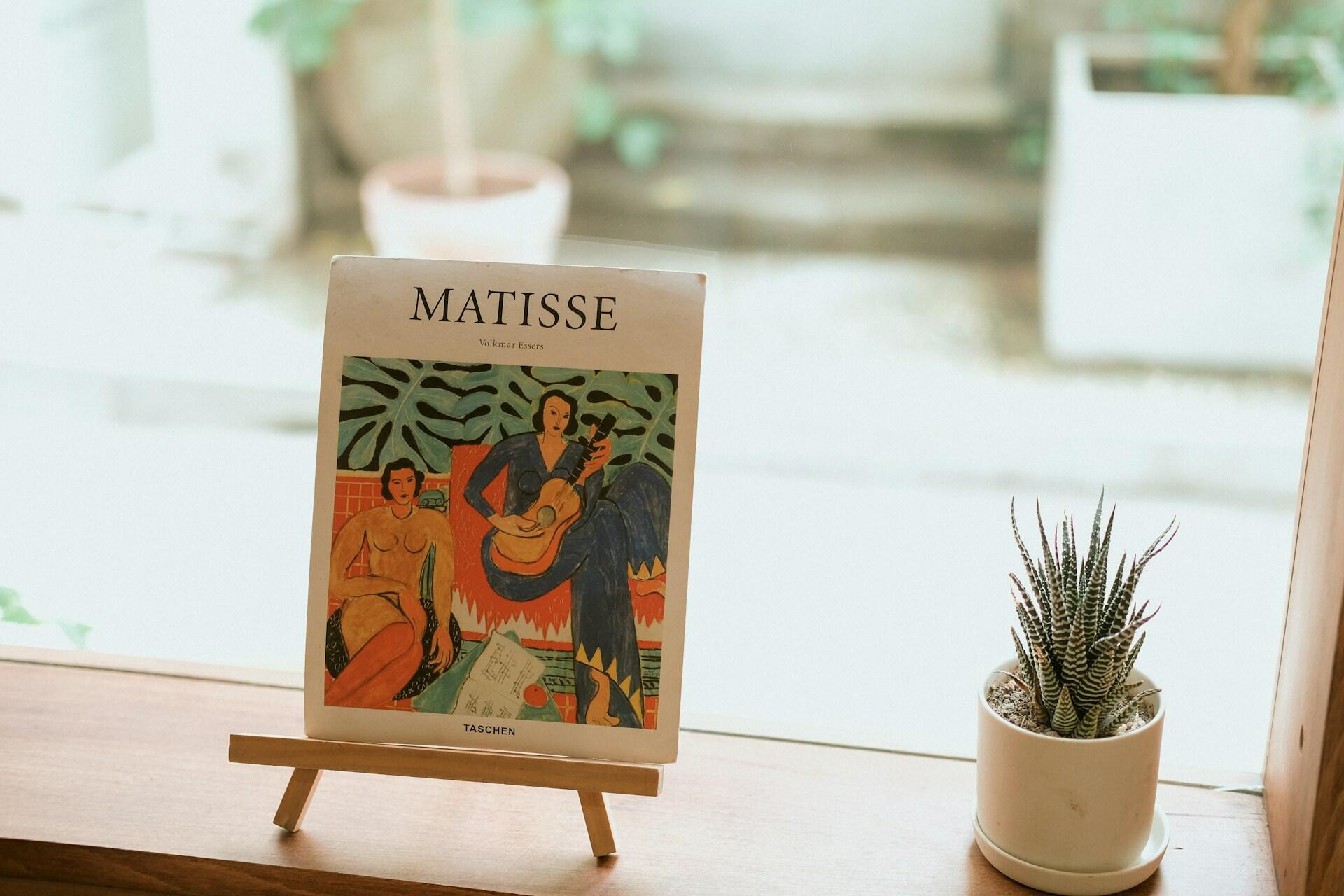 Henri Matisse kunst bok med illustrasjon av fargerike figurer og planter på bord ved vindu foto av Hieu Tran