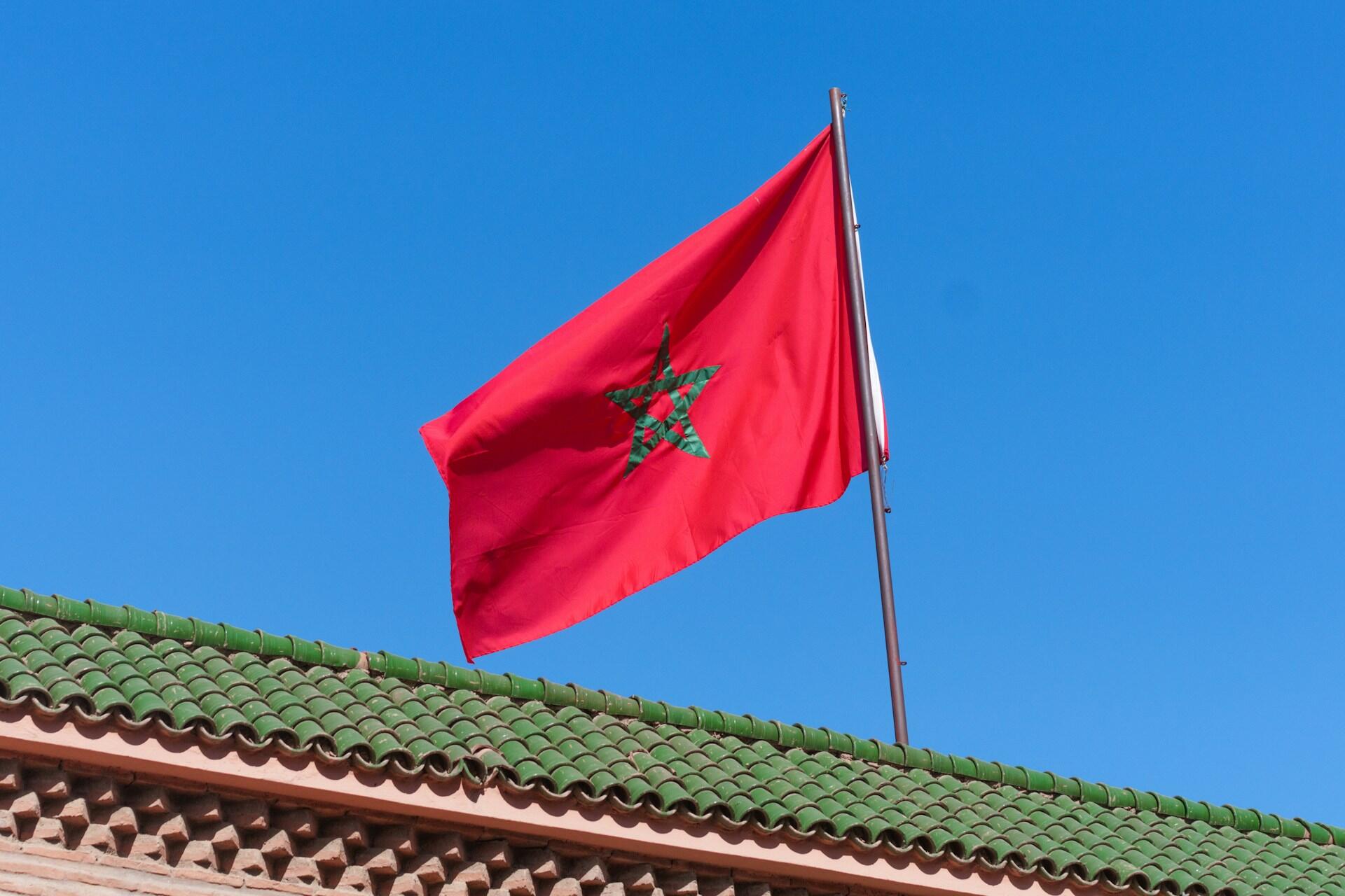 Marokko sitt flagg i vinden med blå himmel bak