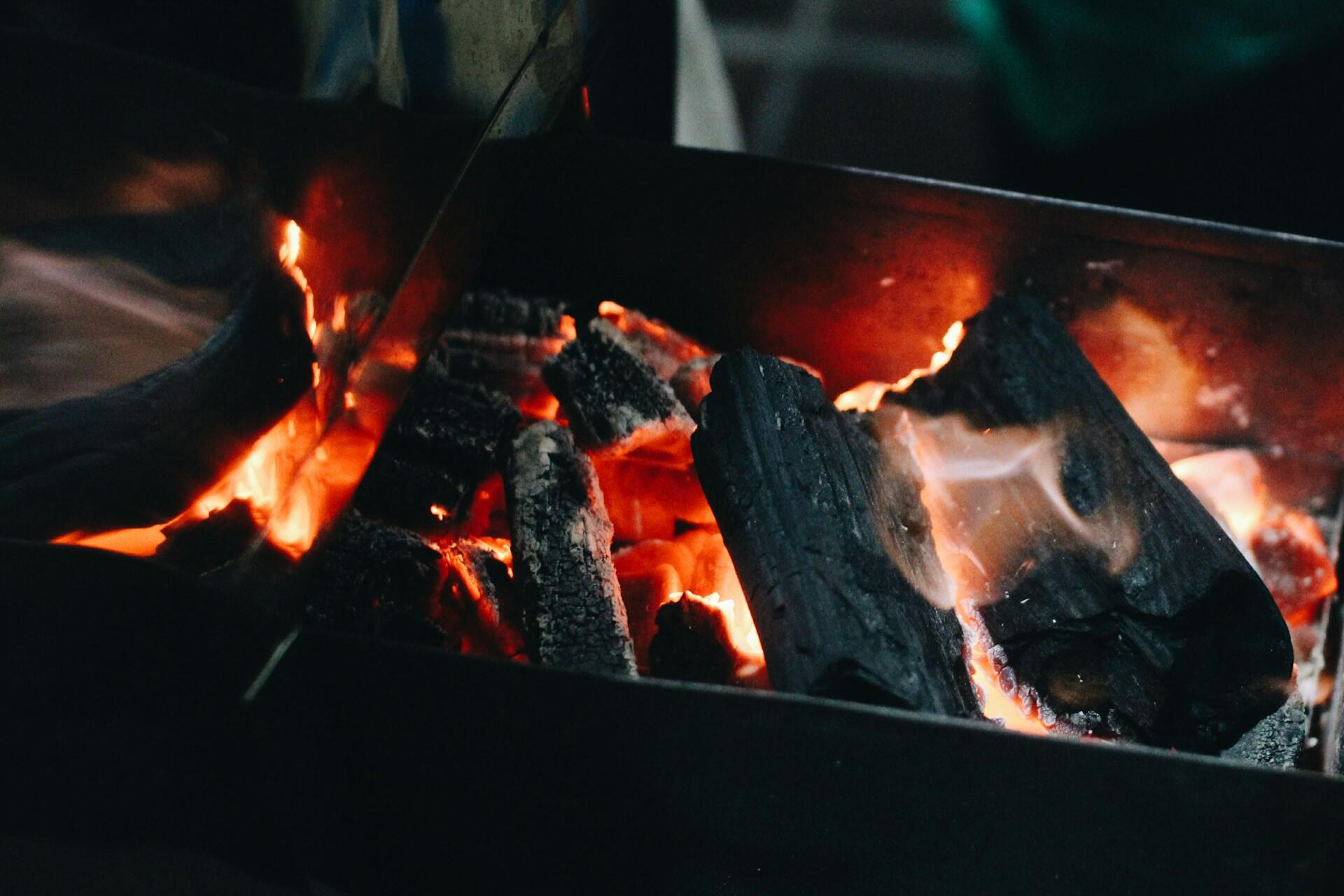 Glødende grillkull med flammer i en kullgrill før maten legges på