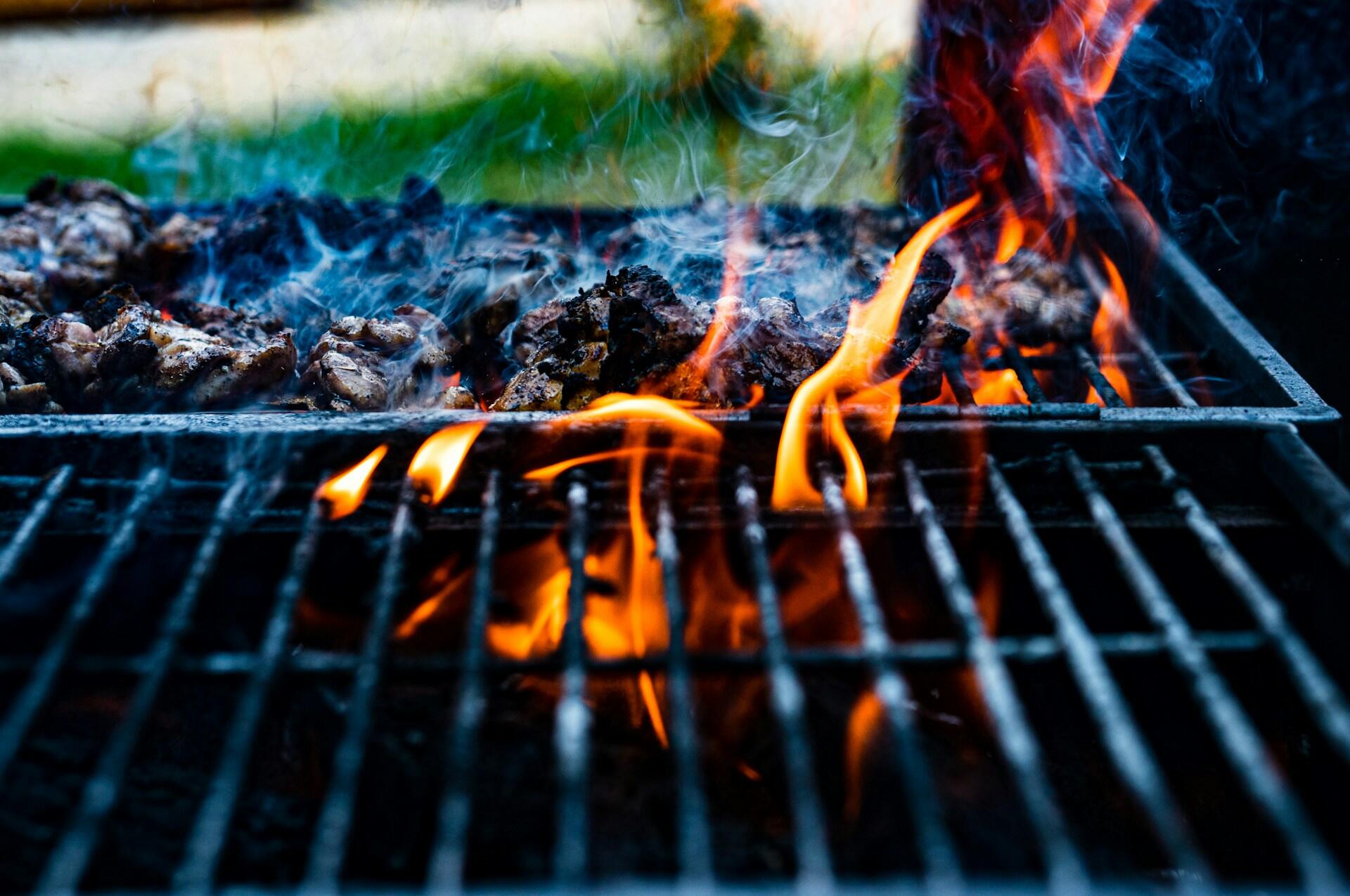 Flammer og røyk fra grill når fett eller olje drypper ned på varmen