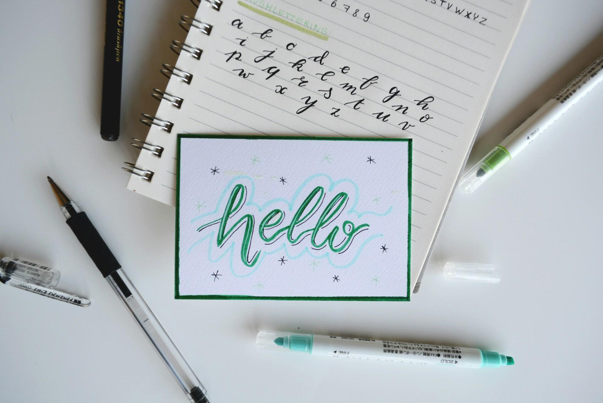 Håndlettering og notatbok med skriveøvelser, symboliserer arbeidet med å lære nær fremtid verb engelsk