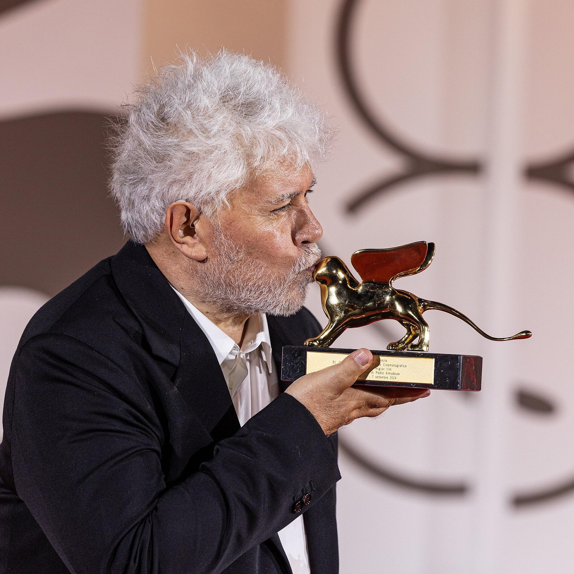 Pedro Almodóvar kysser en filmpris formet som en bevinget løve.