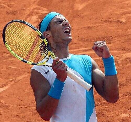 Rafael Nadal jubler med racketen på en rød grusbane.