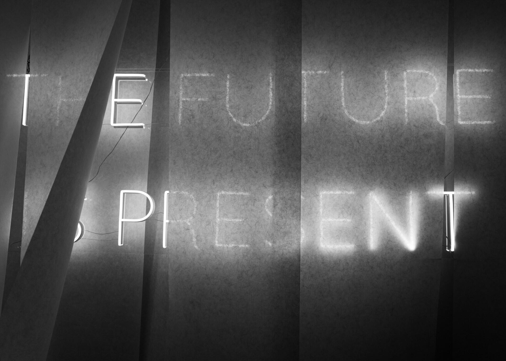 Neonskilt med teksten «the future» og «the present» i mørkt rom