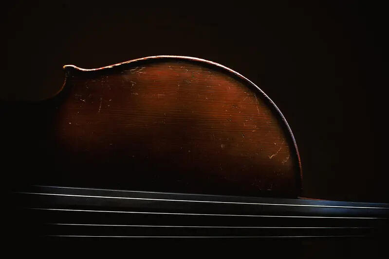 Cello av tre med bue ved siden av instrumentet