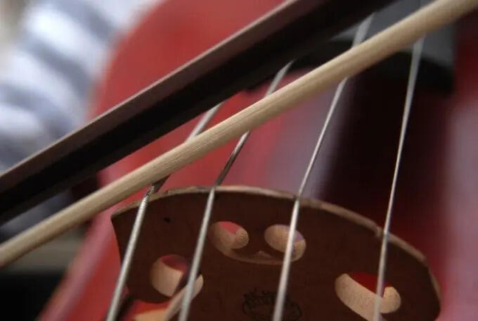 Cello av tre med bue ved siden av instrumentet