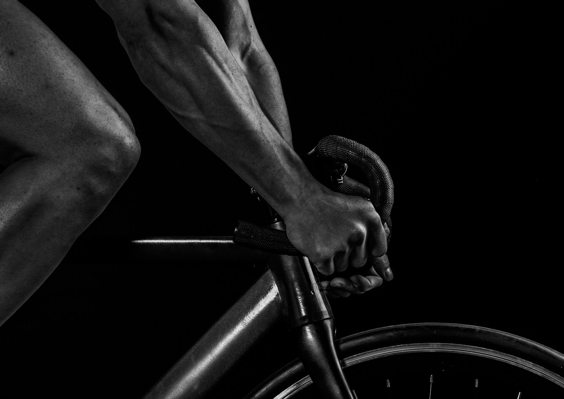 Syklist griper styret på en racersykkel under trening.