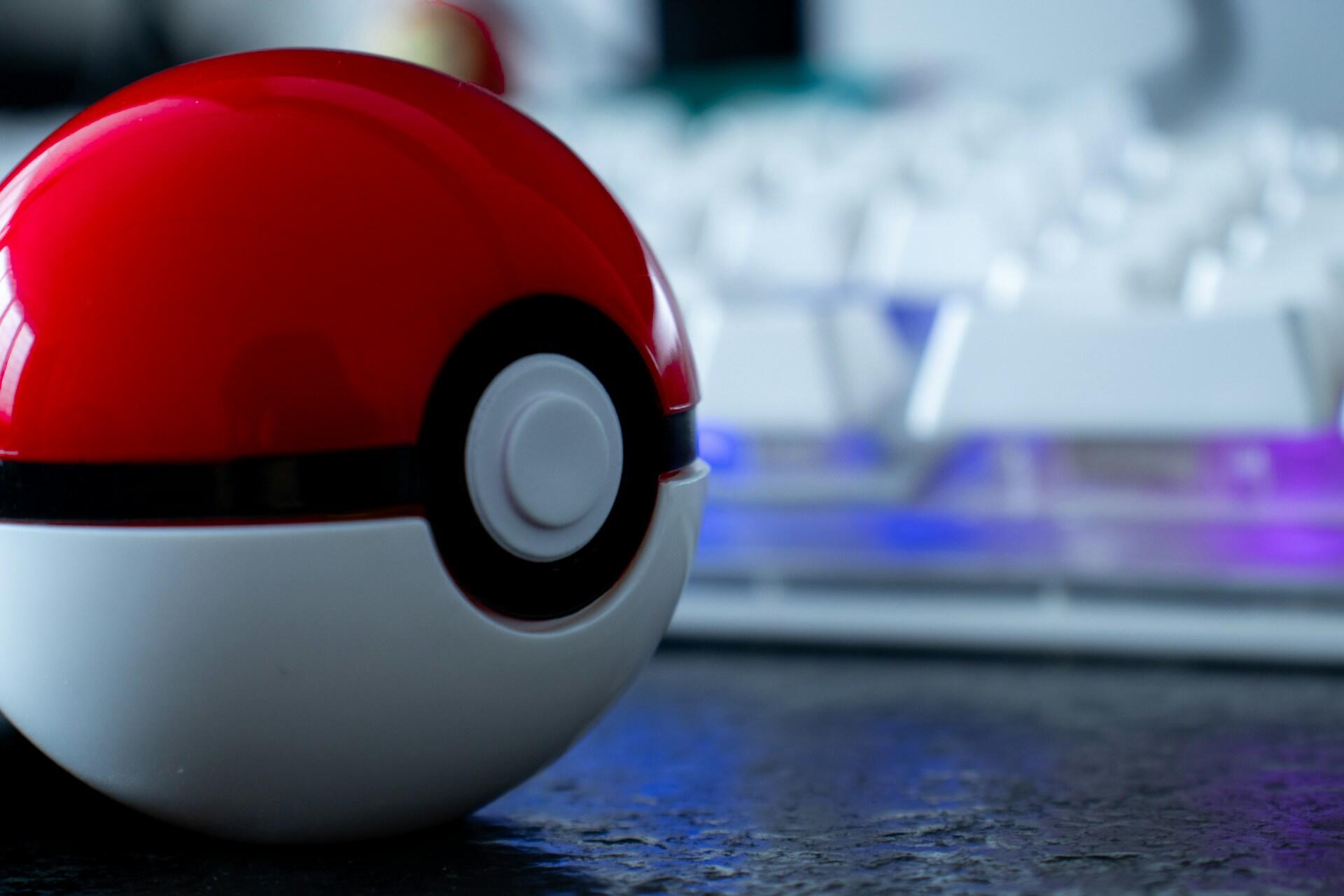 Rød og hvit Poké Ball på et bord med uskarp bakgrunn.