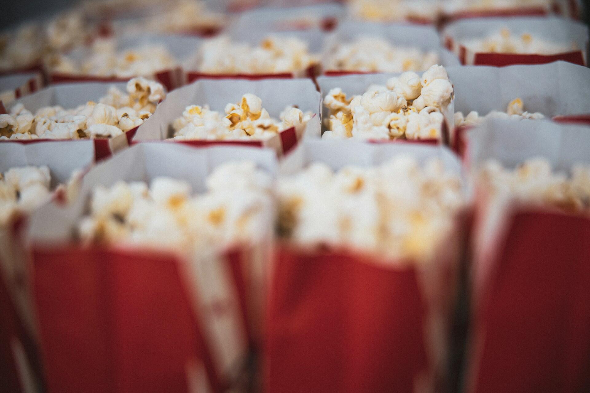 Flere røde beger med popcorn klare til en kinovisning.