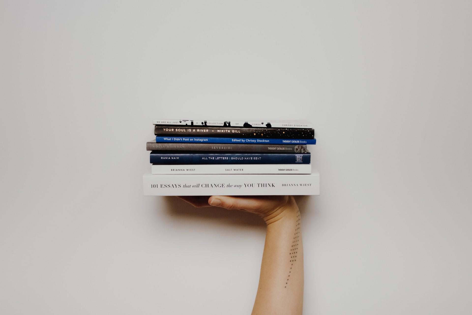 A pile of books held by a hand