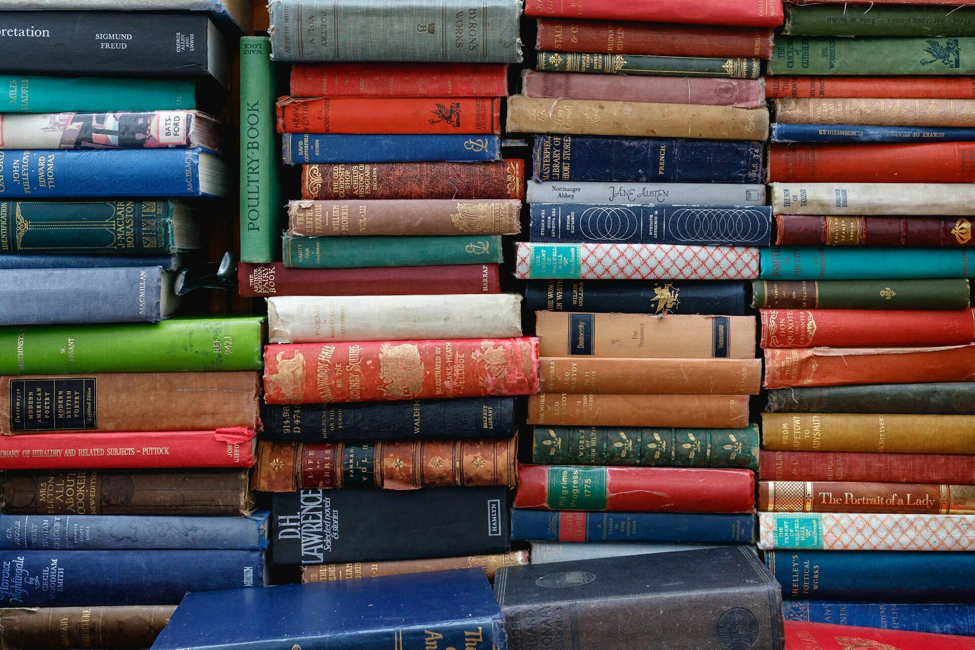 Stacks of worn vintage books with colourful cloth covers