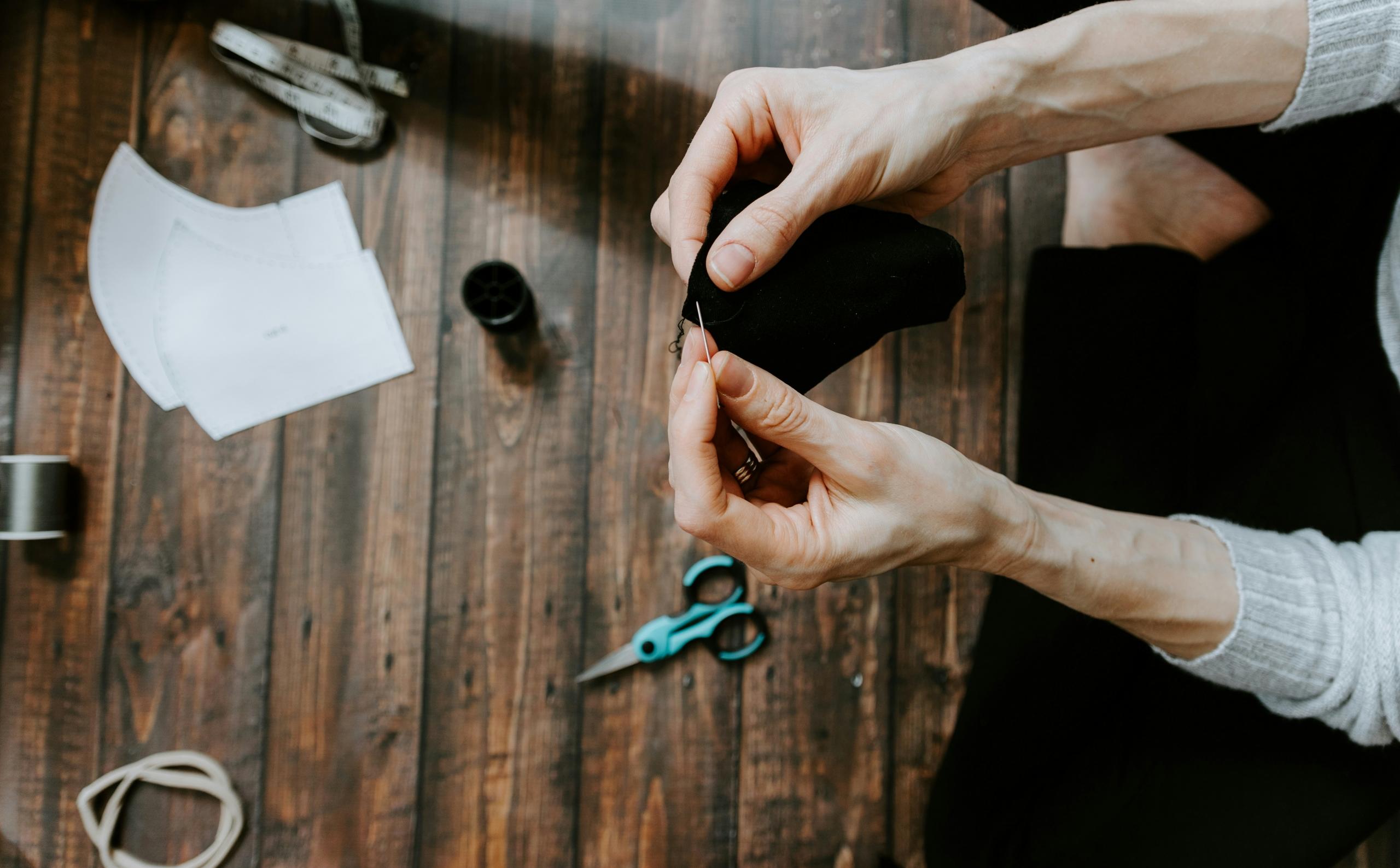 Two hands with piece of cloth and needle