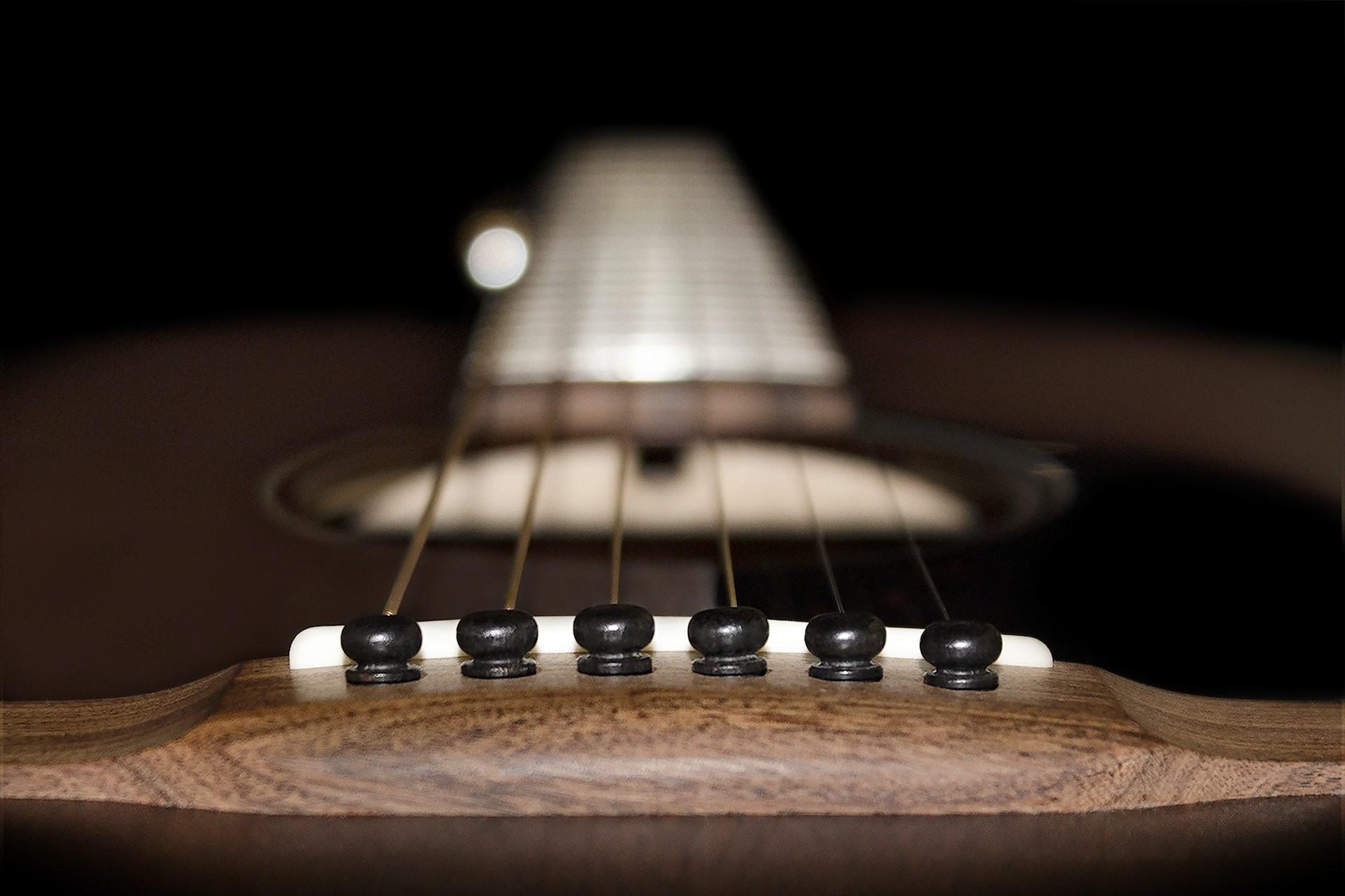 A closeup of an acoustic guitar viewed from the bridge.