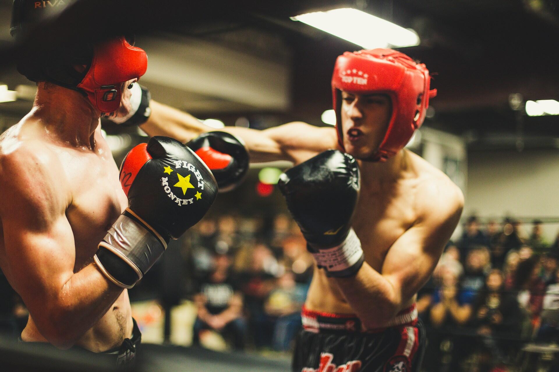 Two boxers wearing headguards and gloves exchanging punches in a ring