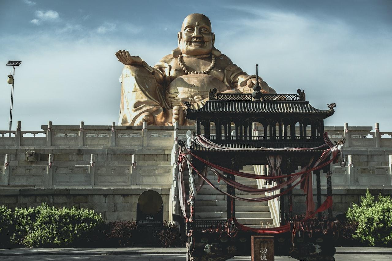 A large statue of Buddha towers over structures at a shrine.