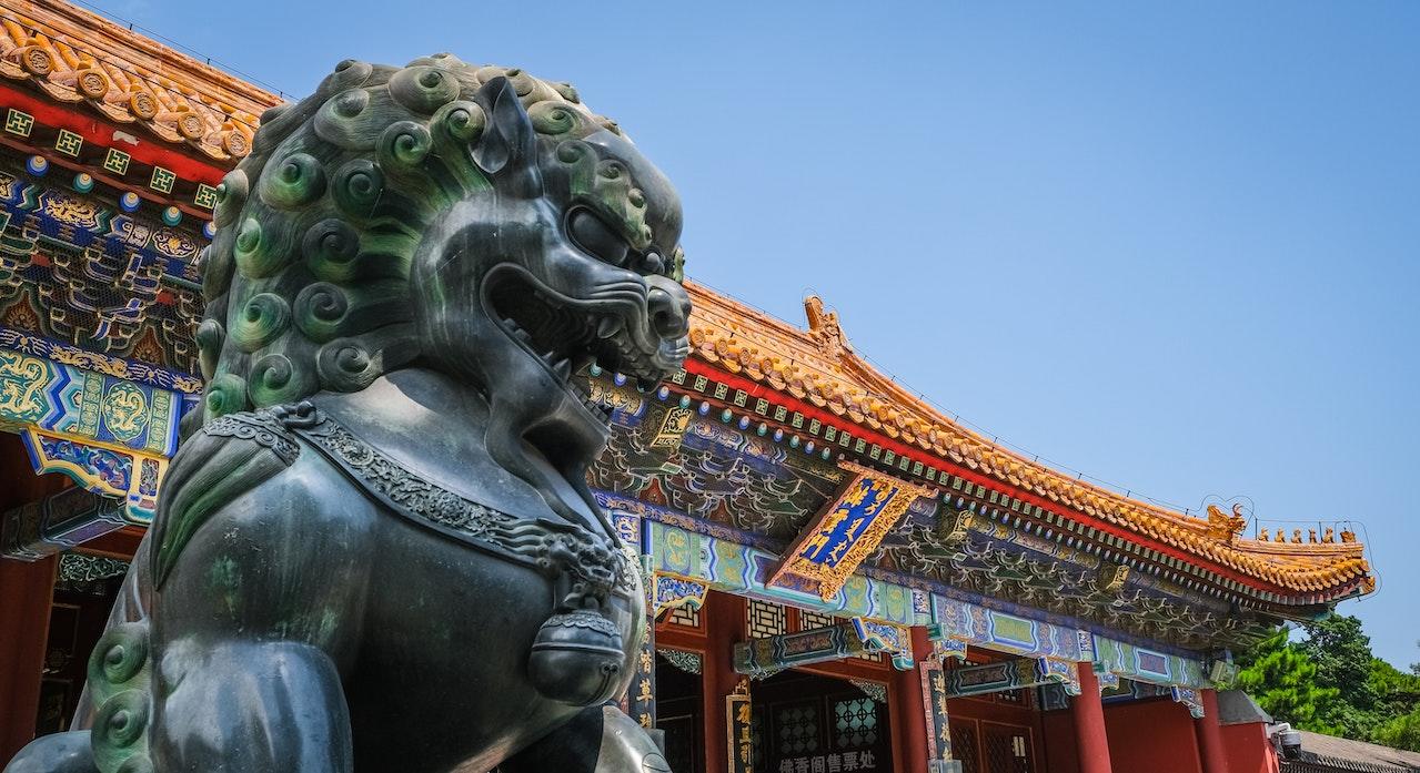 A large statue of a Chinese lion in front of the main Forbidden City structure.