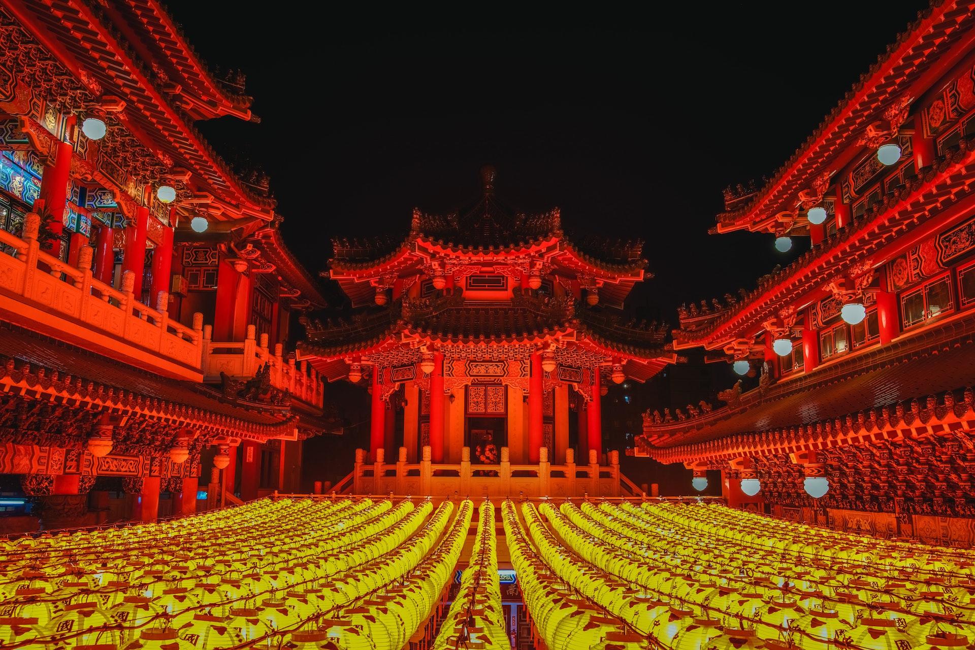 Red lights illuminate a temple and yellow lanterns hang below the camera.