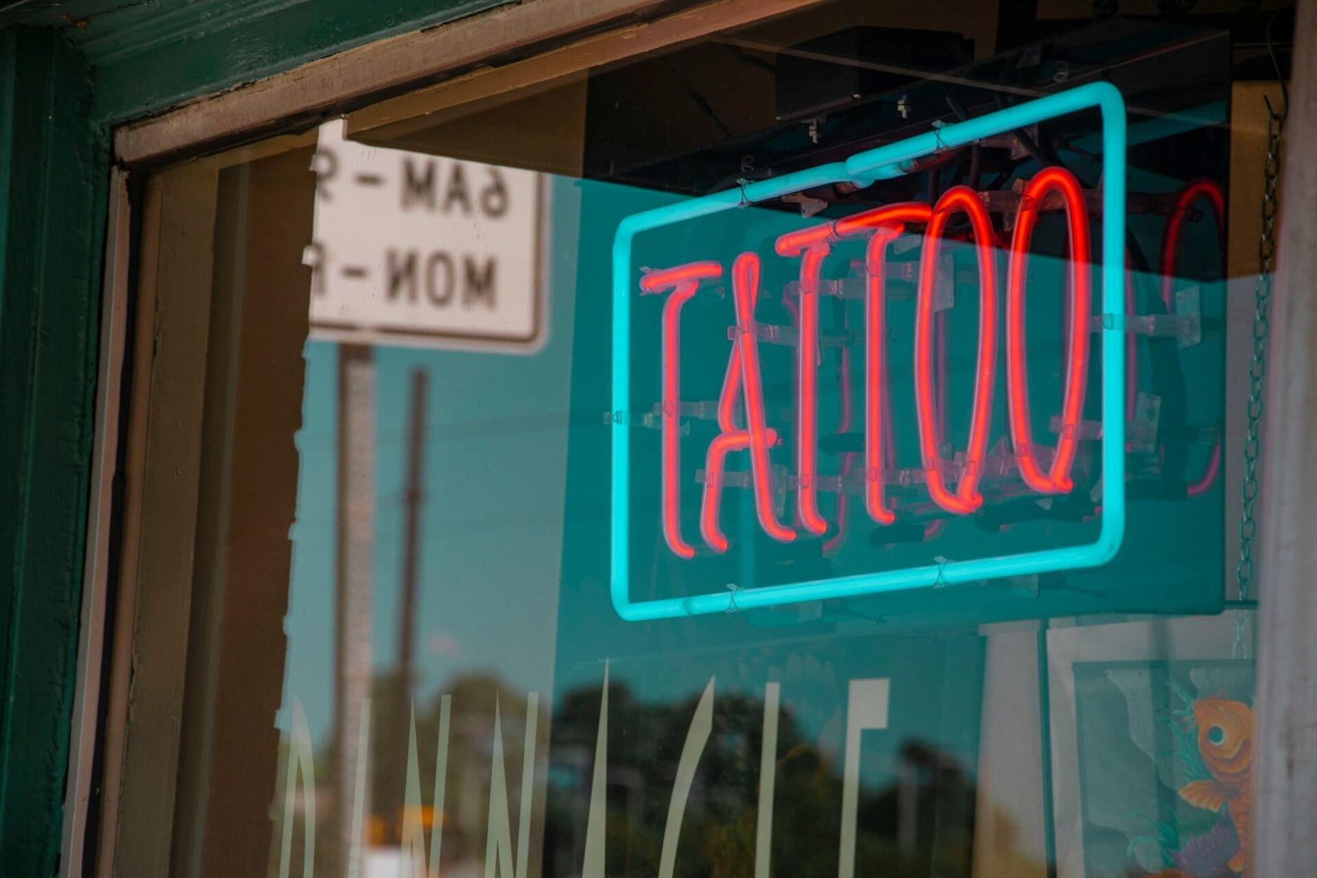 A neon sign outside a tattoo parlour.