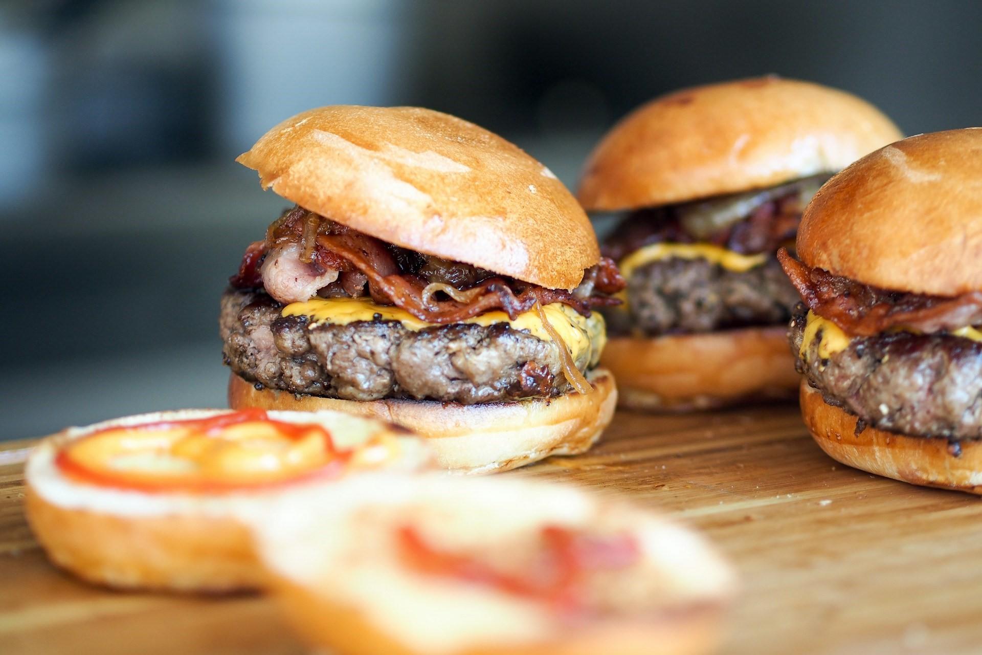 Some burgers on a chopping board.