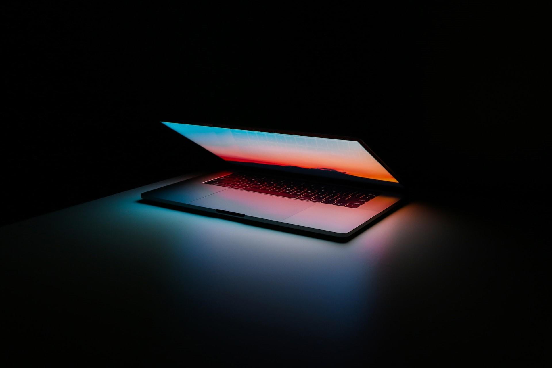 A laptop computer opening in the dark.